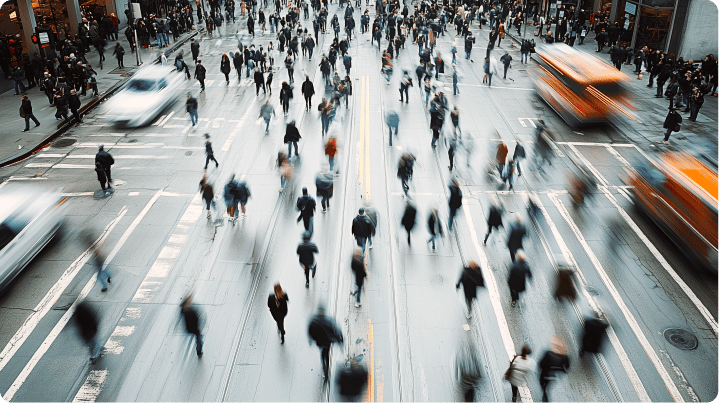 Aerial view of a busy street with pedestrians and fast-moving cars, showcasing constant motion and city life